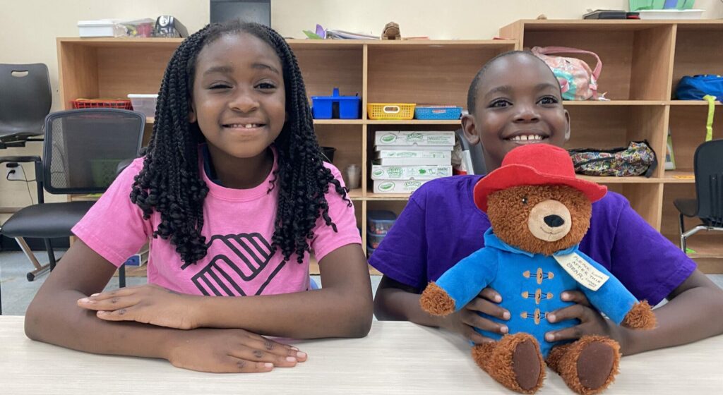 Girls and boy holding teddy bear sitting in a Club classroom.